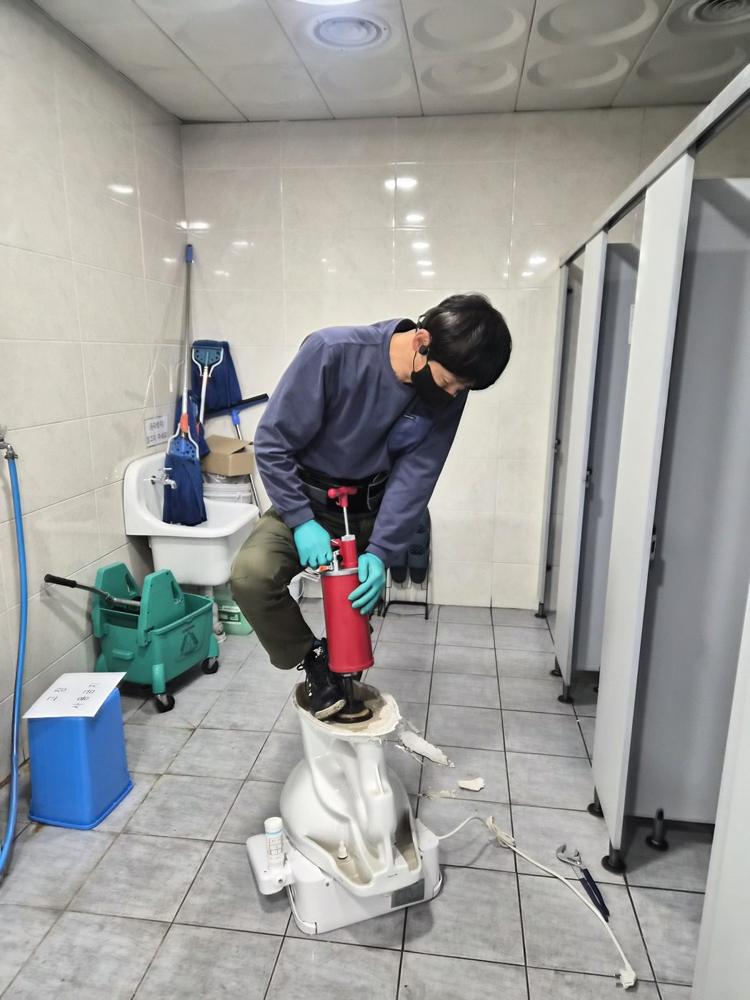 공용 화장실 변기에서 압력 장비로 작업하는 모습