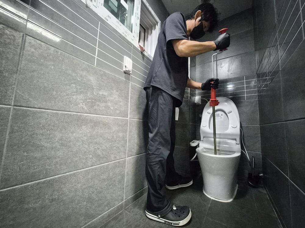 공용 화장실 변기를 장비로 뚫는 작업 모습
